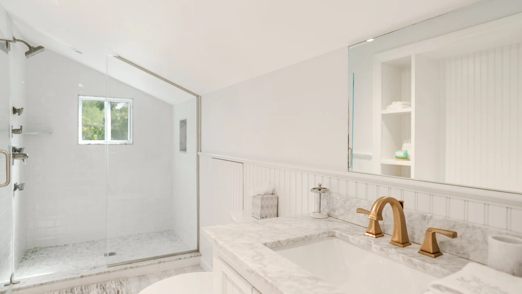 A bright bathroom with a glass shower and a white vanity.