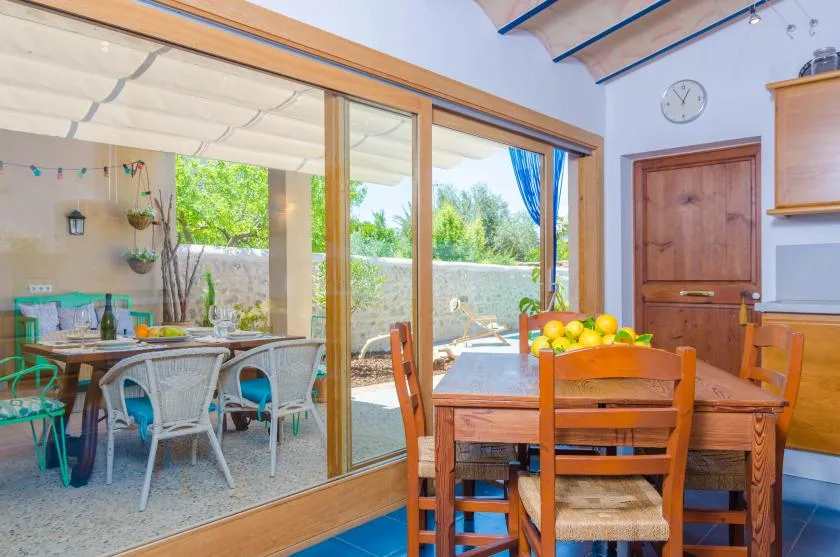 A dining area with a wooden table beside large sliding glass doors opening onto a patio.