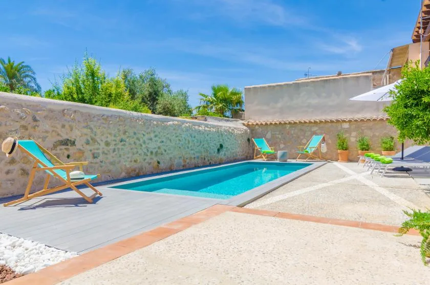 An outdoor pool sits beside a paved patio with lounge seating.