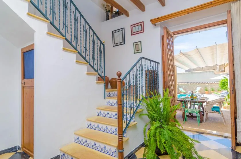 An interior staircase with decorative railings leads toward a bright patio.
