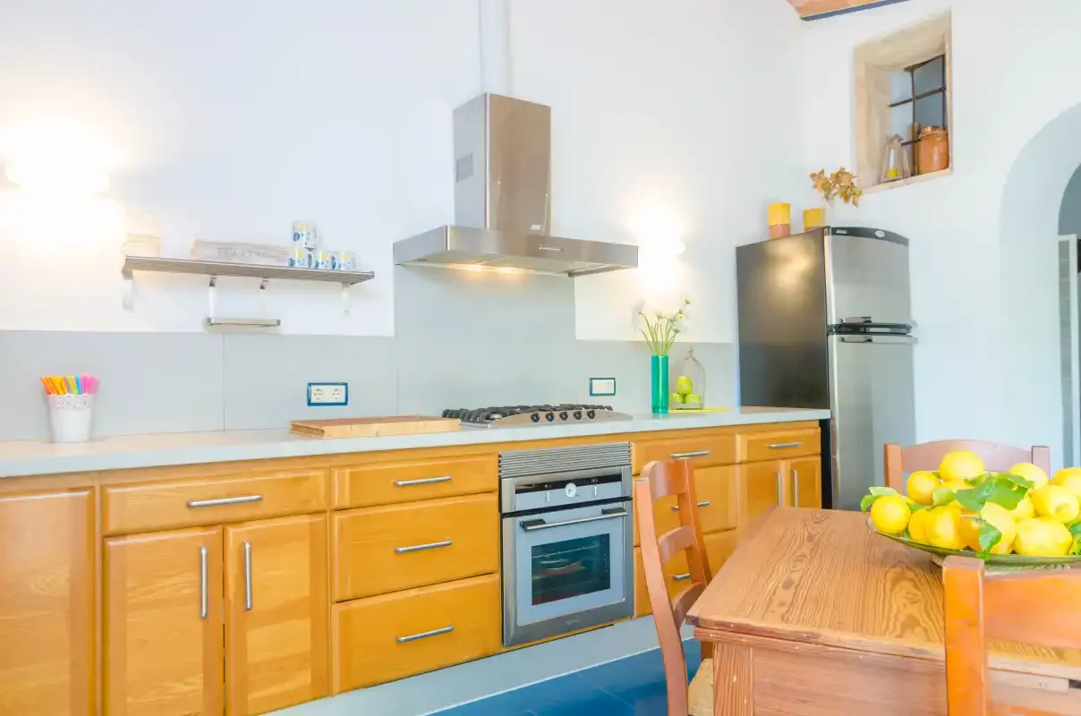 A bright kitchen with wooden cabinetry, a stove, and a dining table.