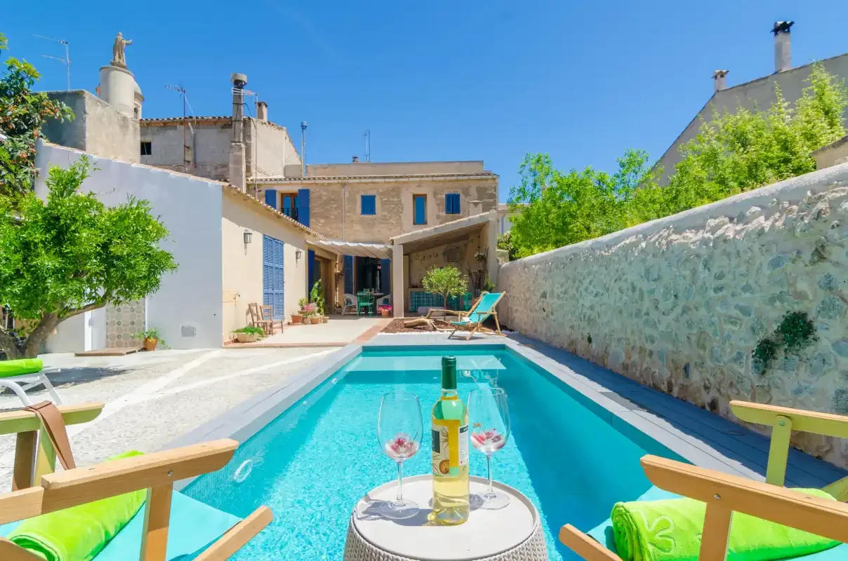 A swimming pool beside a courtyard with seating and greenery.