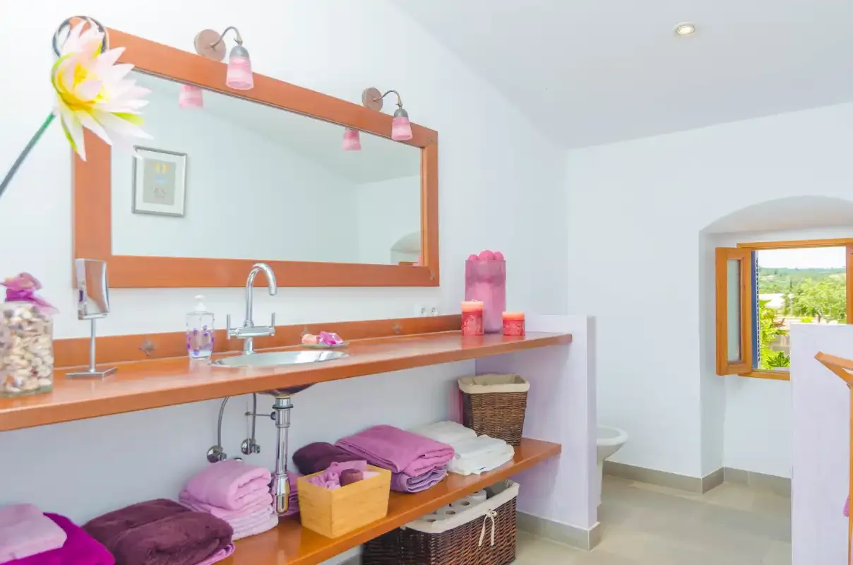 A bright bathroom vanity with a wide mirror and an open window.