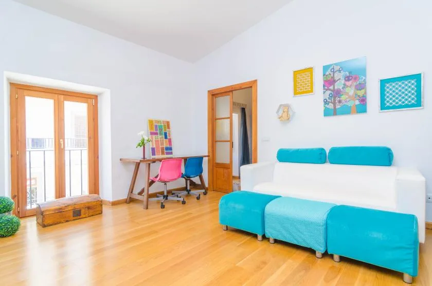 A bright living room with turquoise seating and colorful wall art.