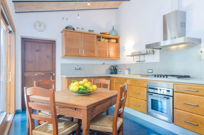 A bright kitchen with wooden cabinets, a dining table, and a cooking range.