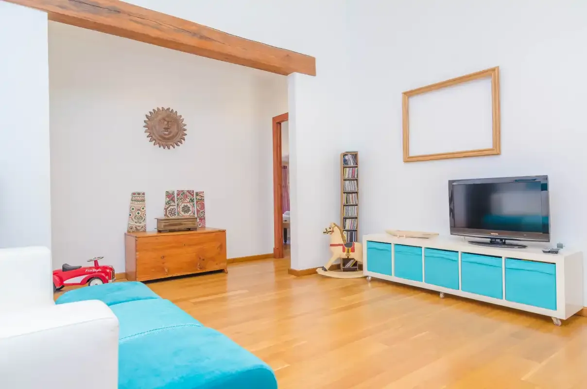 A bright living room with turquoise seating and a television on a low cabinet.