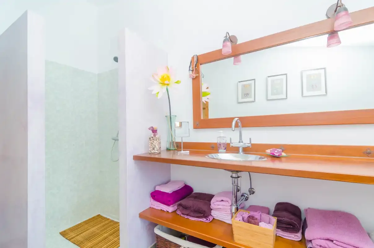 A bright bathroom with a wide sink counter and a shower.