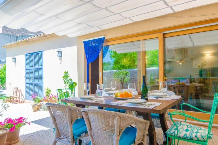 A covered patio dining area with a set table beside large glass doors.