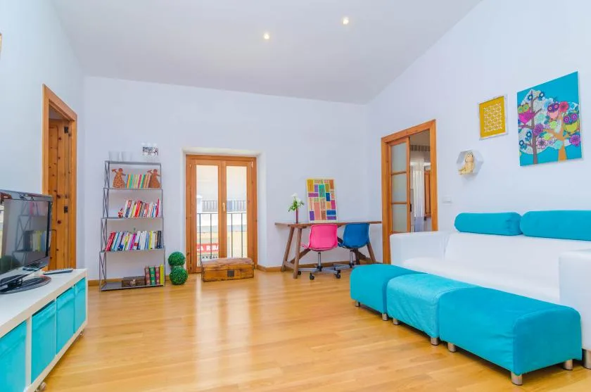 A bright living room with a turquoise sectional and a small desk.