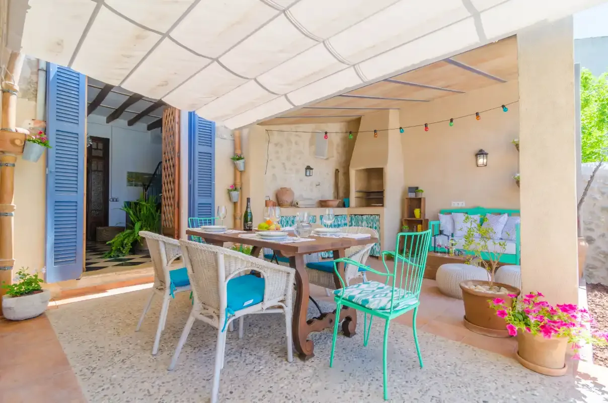 A covered outdoor dining area with a table and colorful seating.