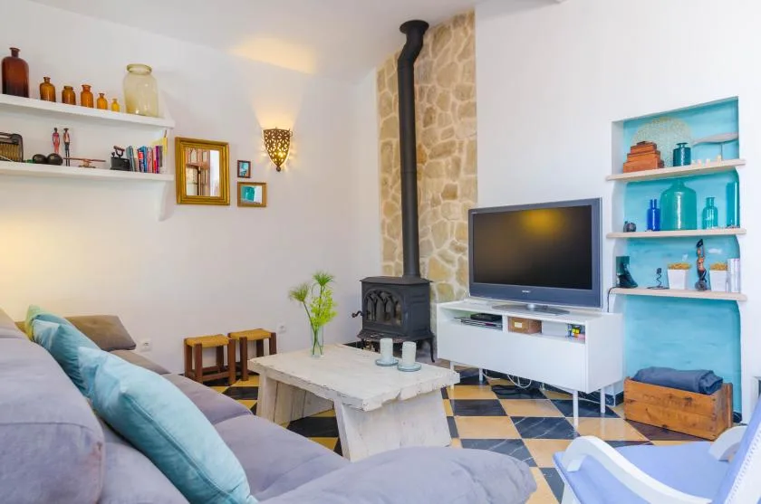 A living room with seating, a television, and a wood-burning stove.