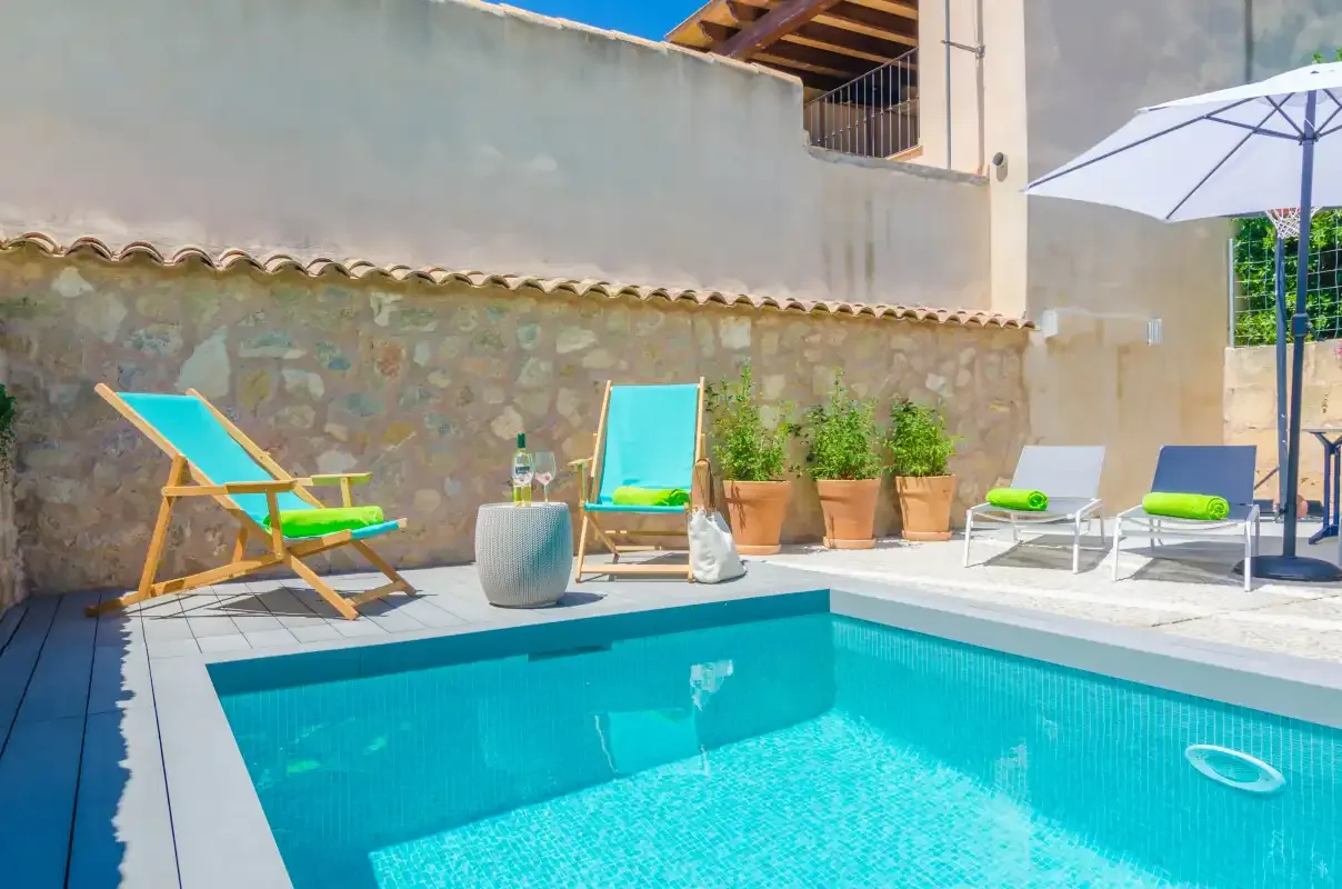 A sunny poolside patio with lounge seating and potted plants.