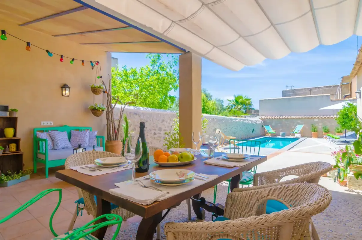 A shaded outdoor dining area opens onto a pool and garden.