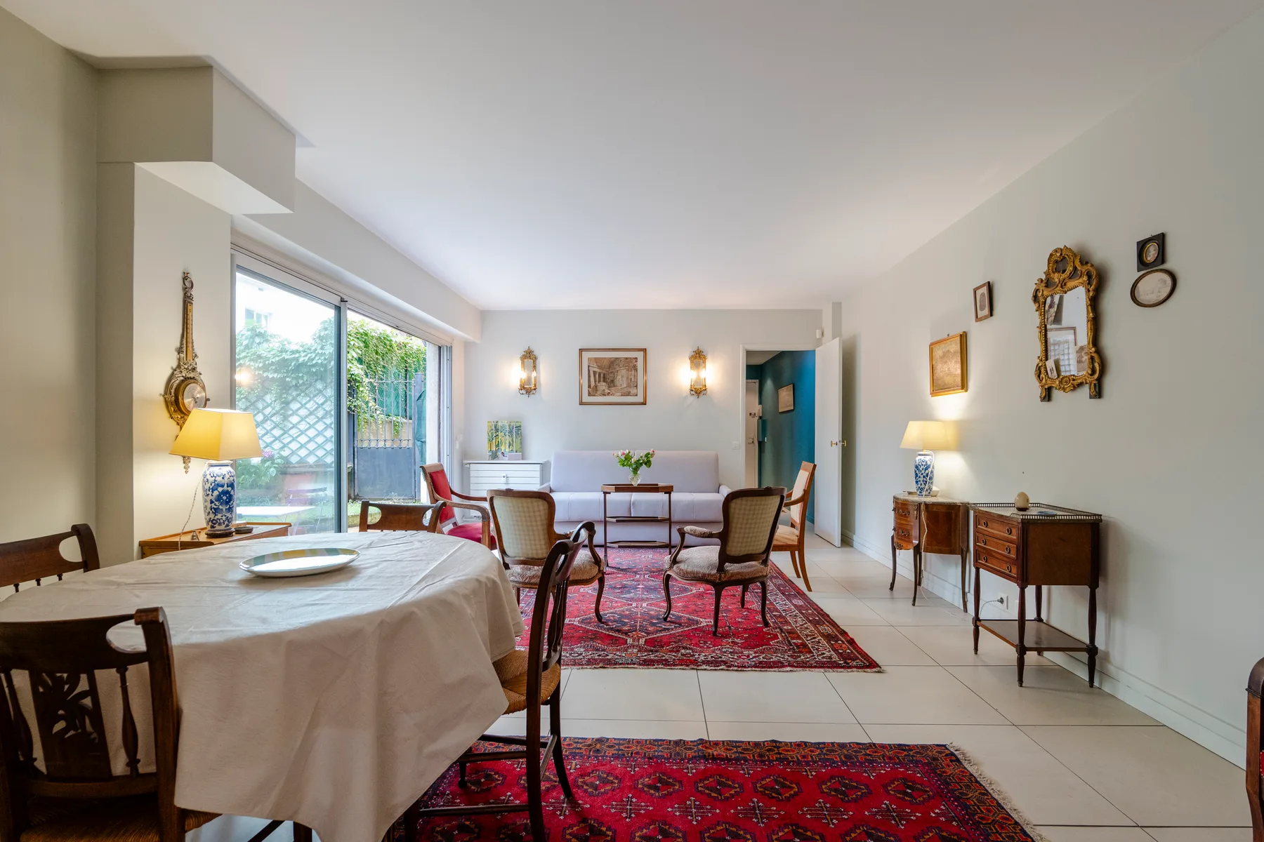 A bright dining room with a table, chairs, and patterned rugs.