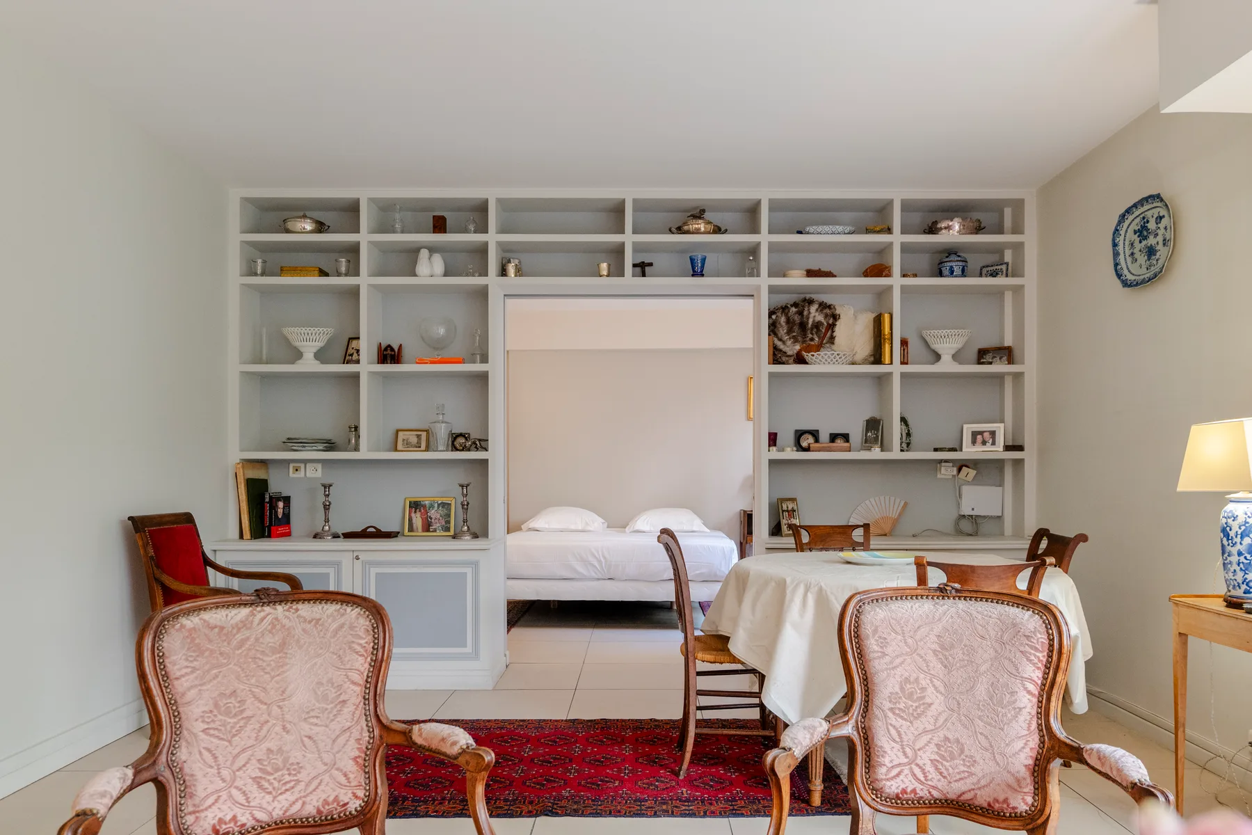 A bedroom with a bed, built-in shelving, and upholstered seating.