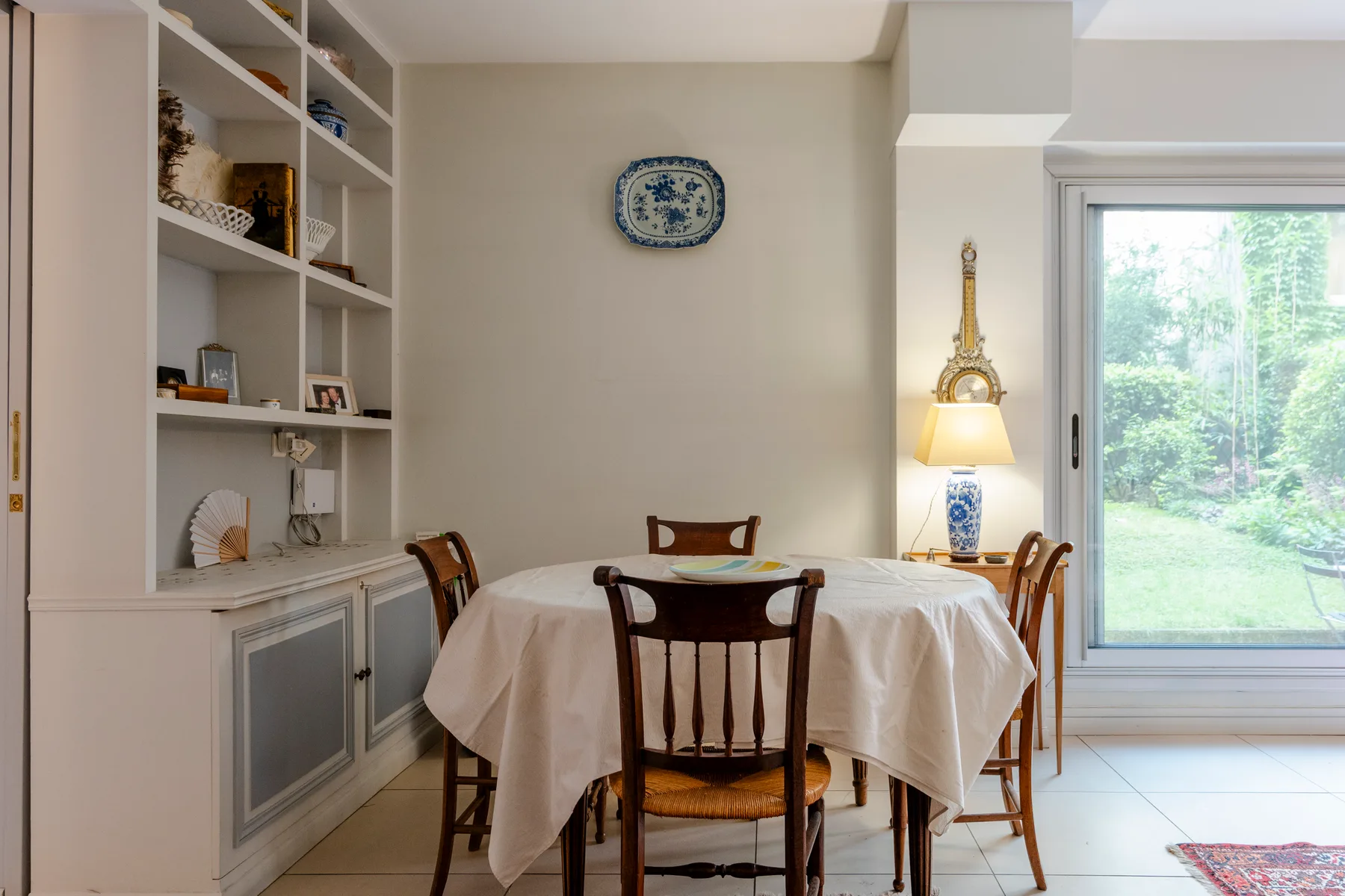 A dining area with a round table, wooden chairs, and built-in shelving.