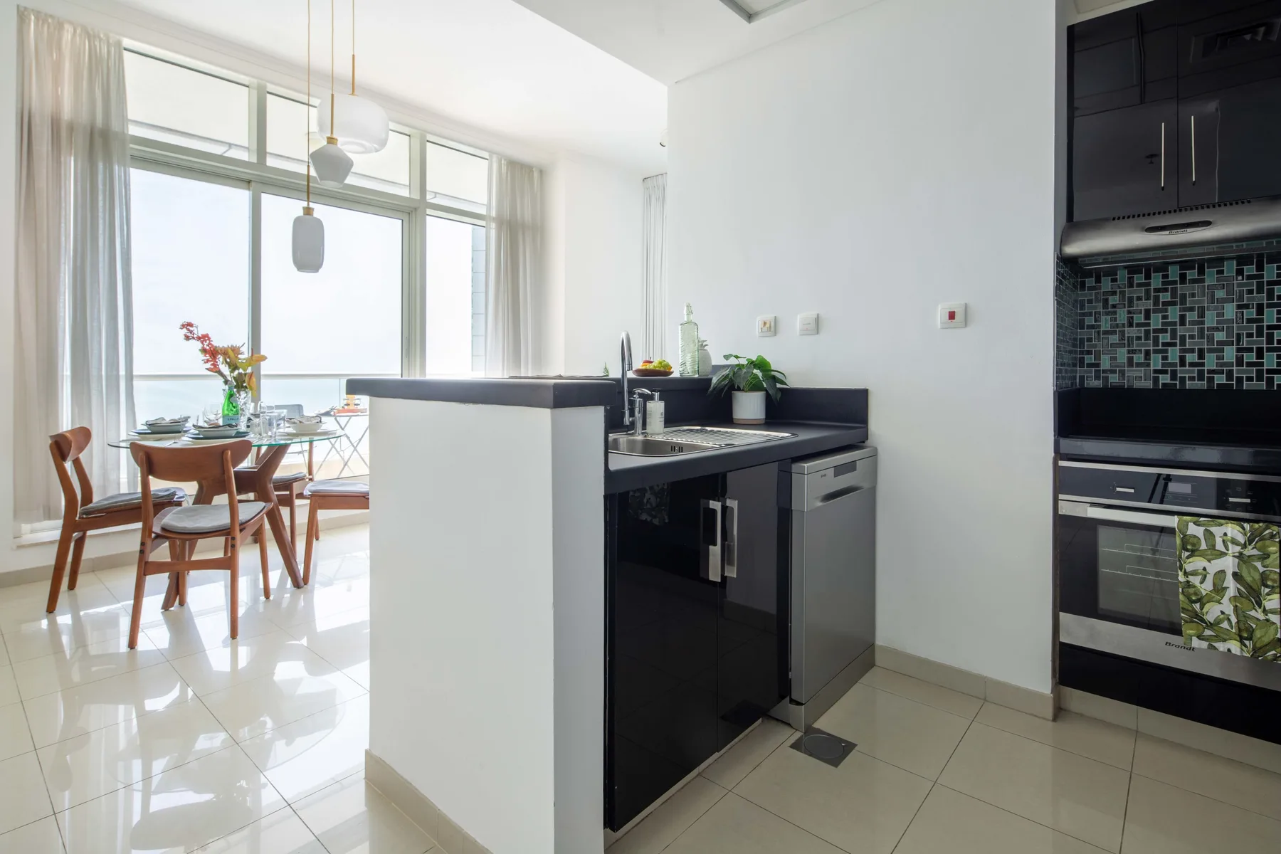Una cocina moderna da a un comedor junto a grandes ventanales.
