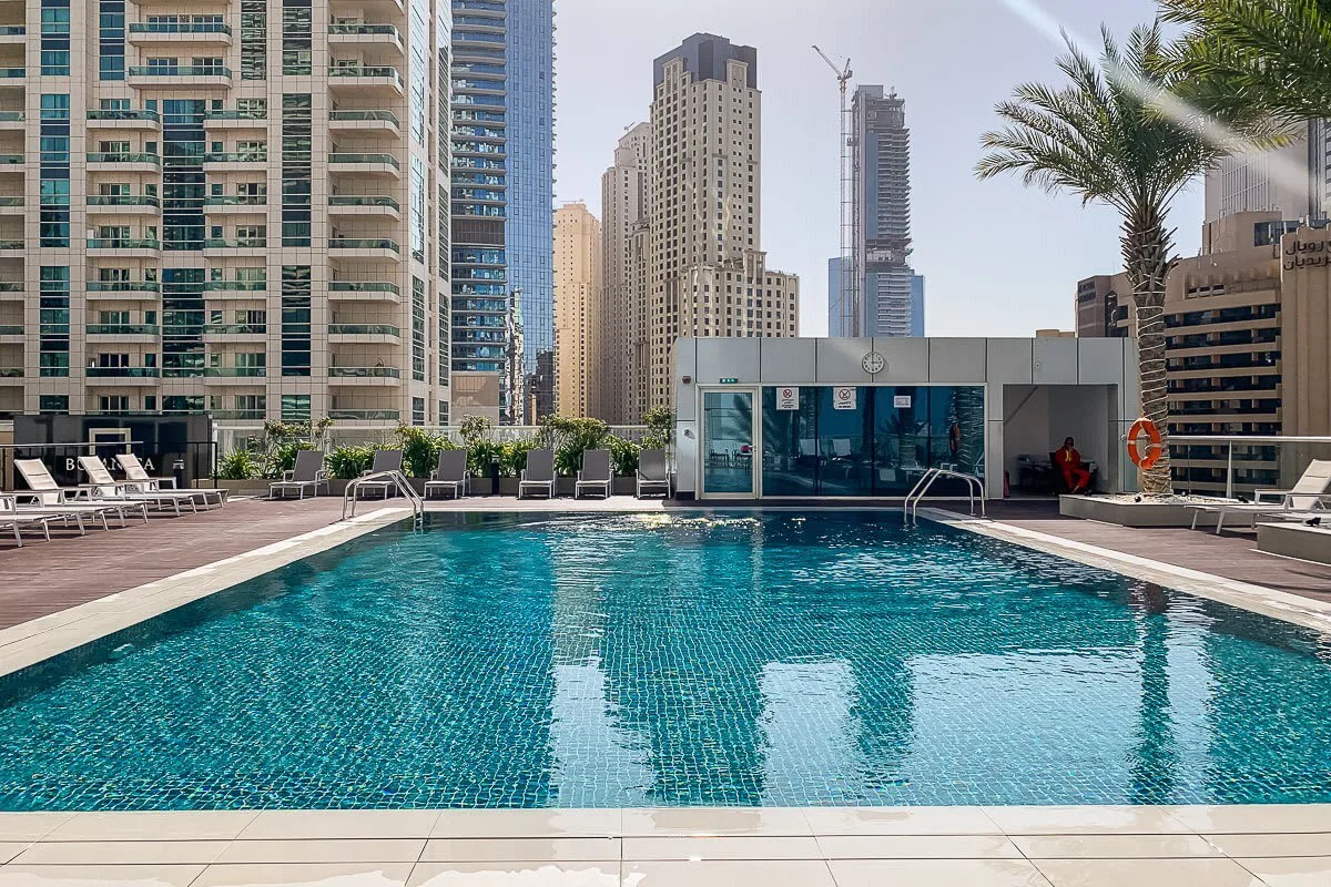 Una piscina en una azotea está rodeada de edificios altos y asientos junto al agua.
