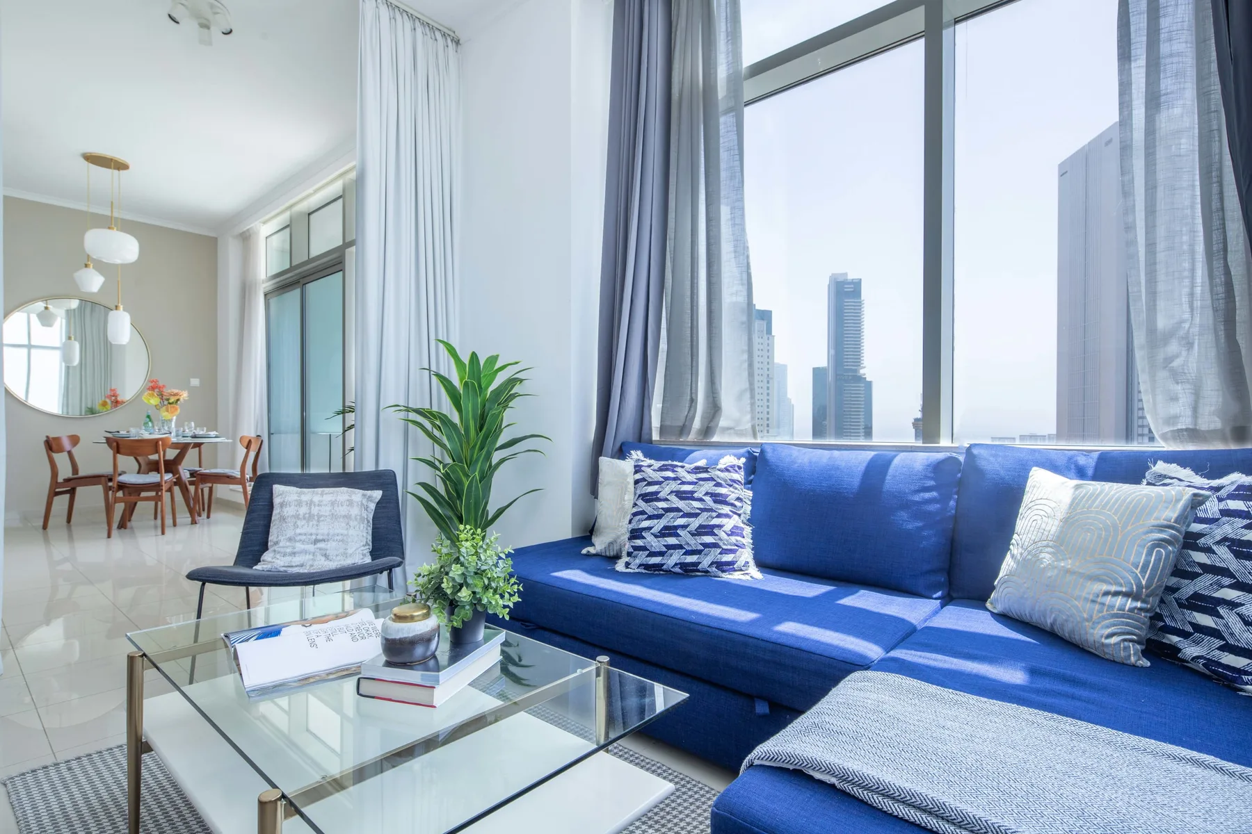 Una sala luminosa tiene asientos azules junto a grandes ventanas con vistas a edificios de la ciudad.