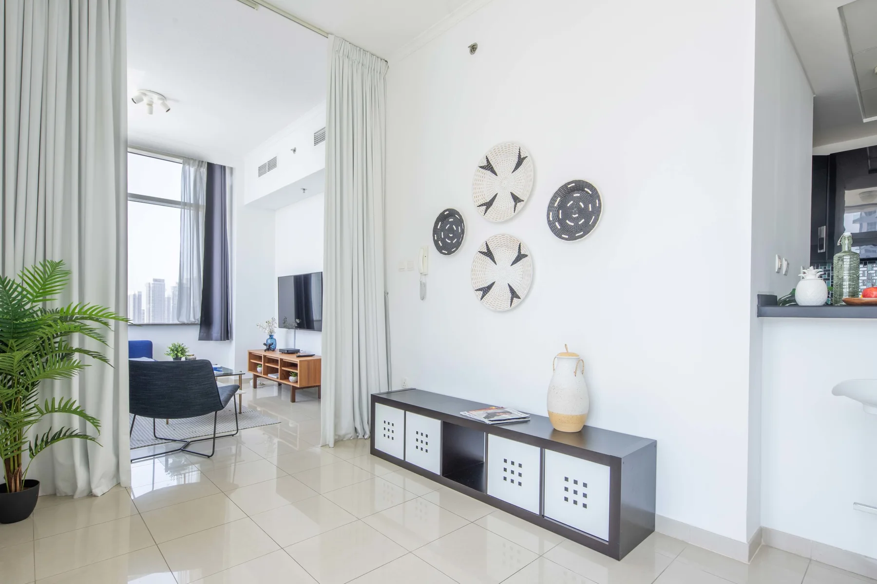 Una sala luminosa con un mueble bajo y asientos junto a una ventana grande.