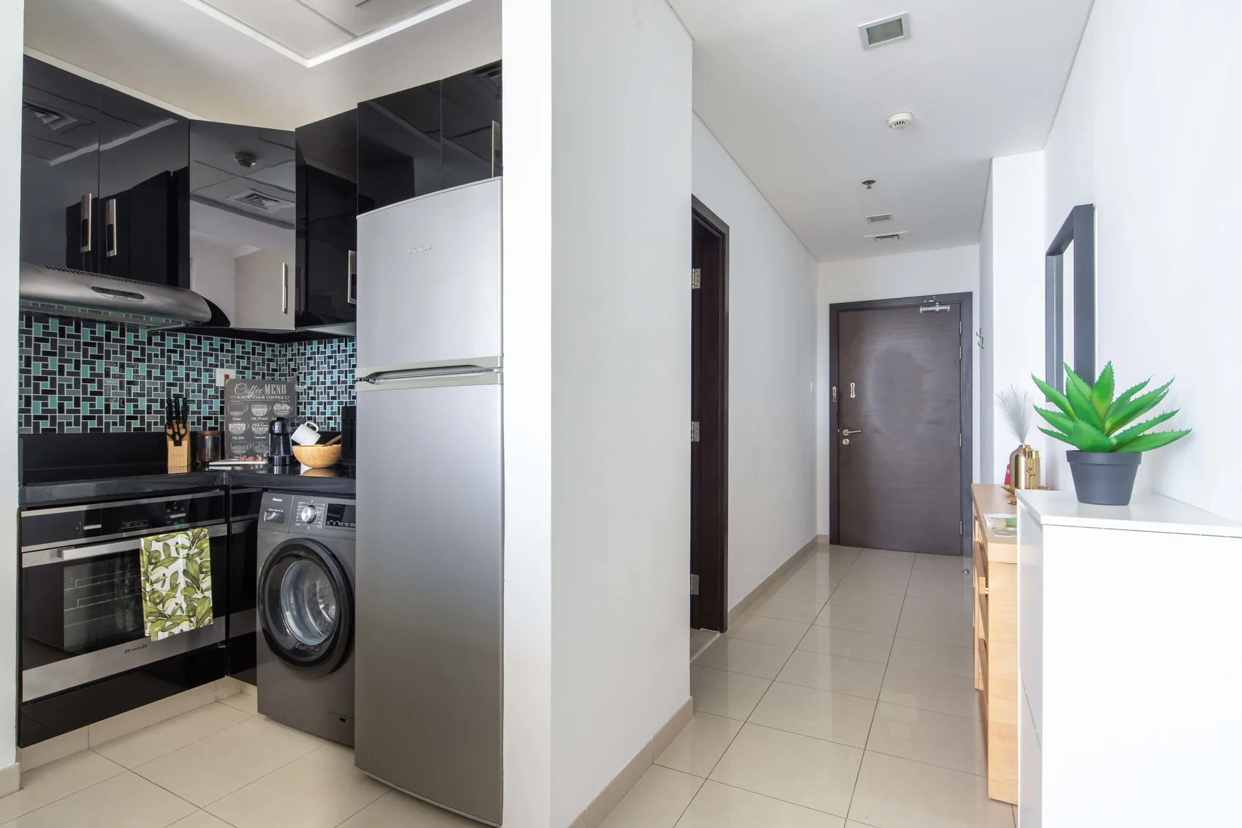 Una cocina compacta da a un pasillo de baldosas con una planta en maceta.
