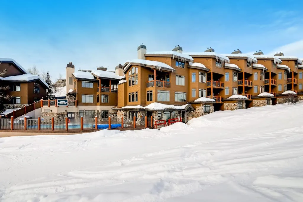 Una hilera de edificios de tonos anaranjados se alza detrás de una pendiente nevada.