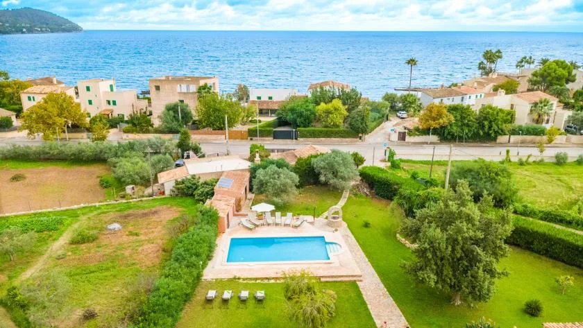 Aerial view of a seaside property with a swimming pool and green grounds.
