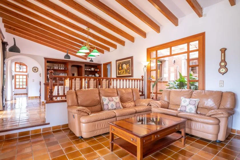 A living room with leather seating, a wooden coffee table, and exposed ceiling beams.