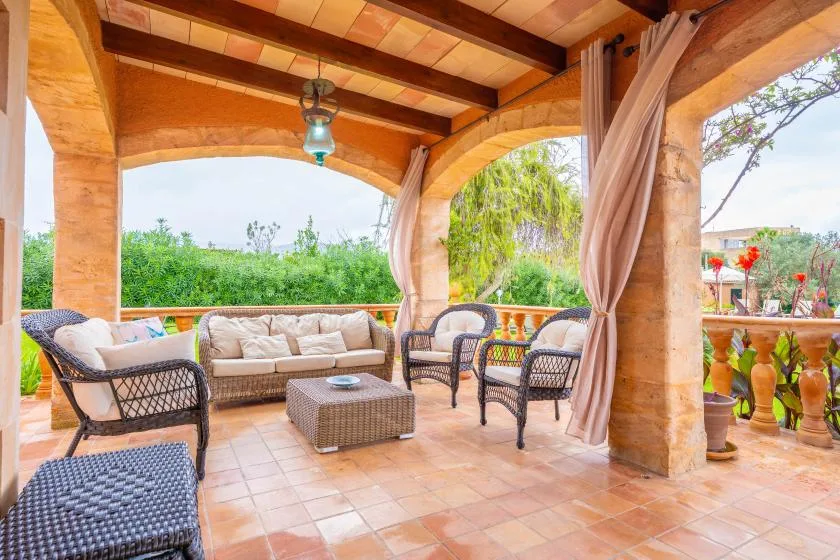 A covered outdoor seating area with cushioned furniture and views of greenery.