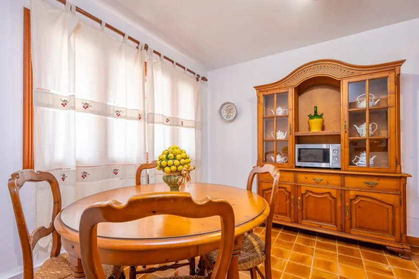 A dining room with a wooden table, chairs, and a large display cabinet.