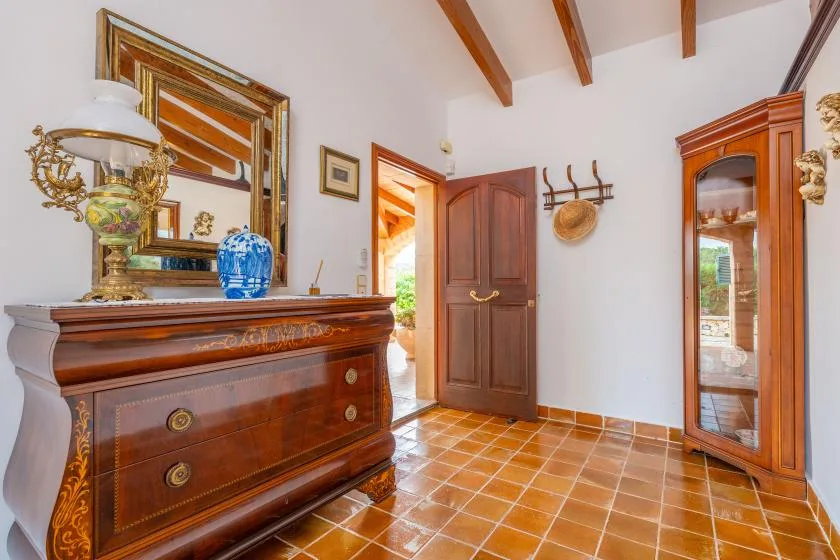 A furnished interior with wooden storage furniture, a mirror, and an open doorway.