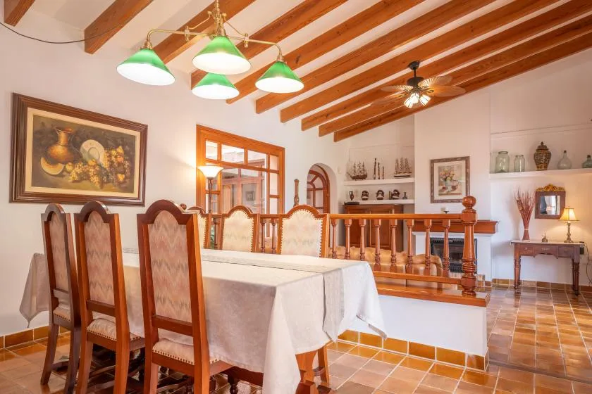 A dining room with a long table, wooden seating, and exposed ceiling beams.