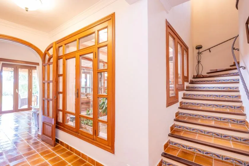 A tiled interior hallway with wooden-framed glass doors beside a staircase.