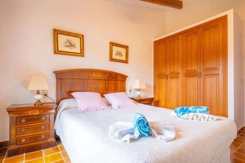 A bedroom with a large bed, wooden headboard, and matching wardrobe.