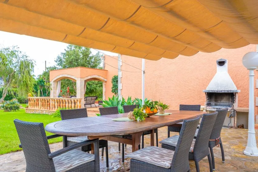 Outdoor dining patio with a long table and a built-in barbecue fireplace.