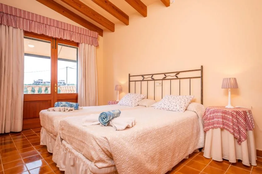 A bedroom with two beds, bedside tables, and a window with curtains.
