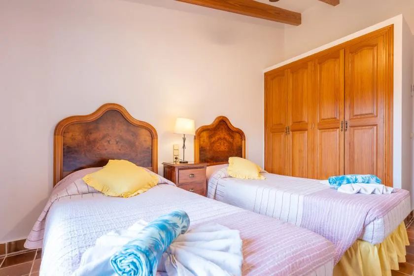 A bedroom with two beds and wooden wardrobes.