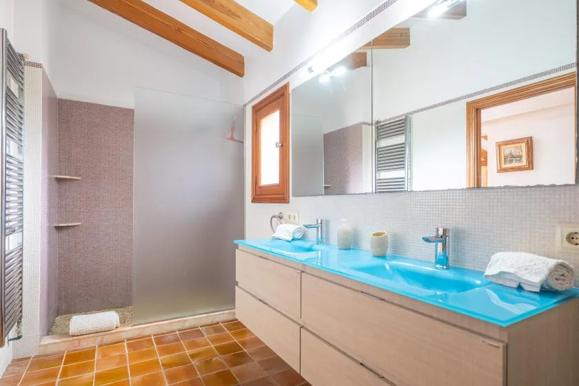 A bright bathroom with a long blue countertop and large mirror.