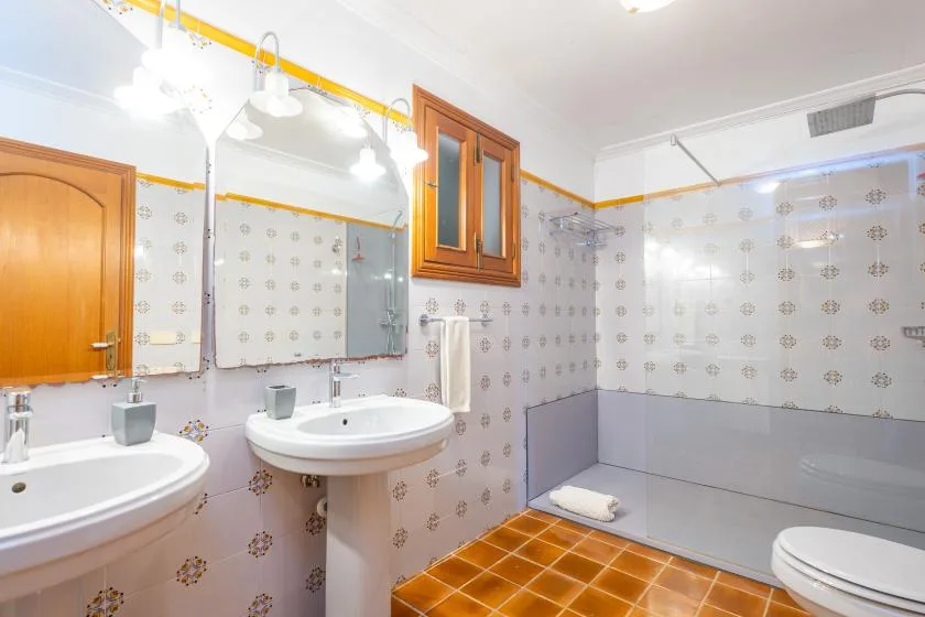 A tiled bathroom with sinks, a bathtub, and a small window.