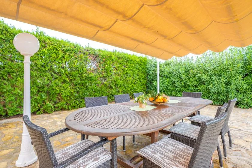 An outdoor dining area with a long table and seating beneath a fabric canopy.