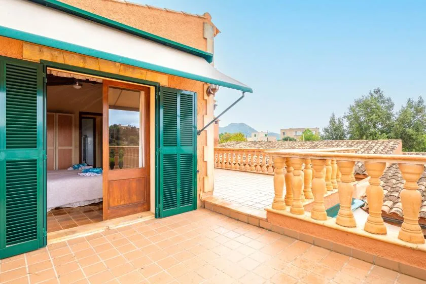 A tiled terrace with green shutters beside an open bedroom doorway.