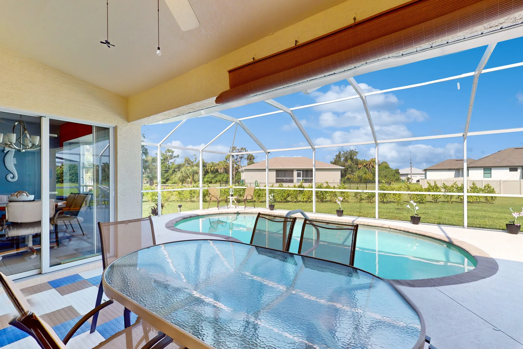 A screened patio with a swimming pool and glass-top dining table.