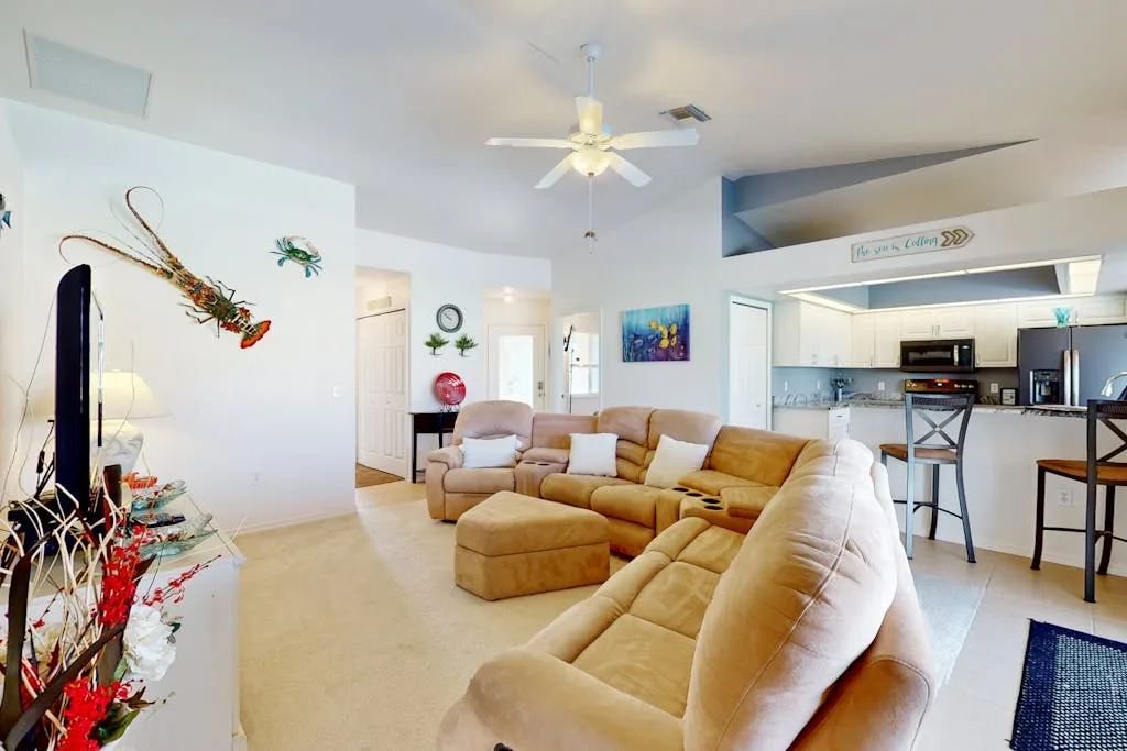 A bright living room with beige seating and an open kitchen.