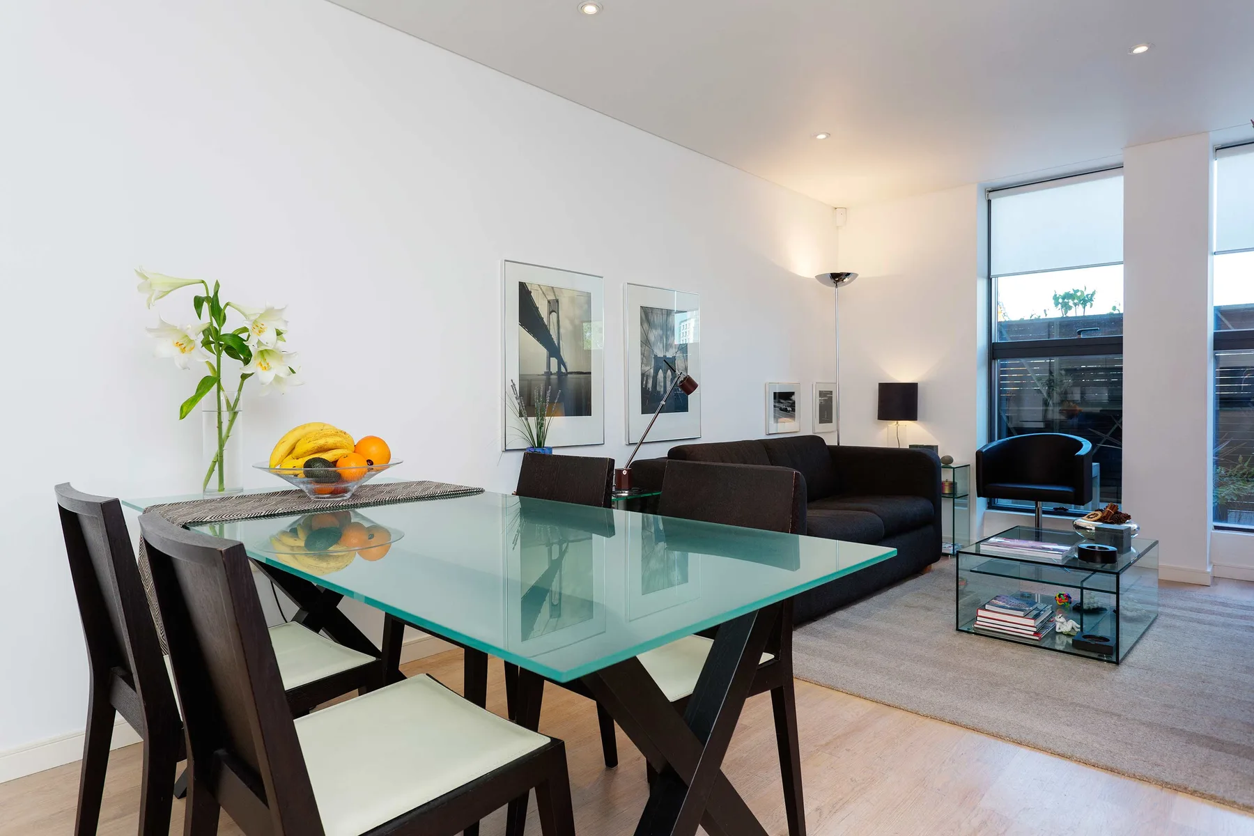 A dining area with a glass table and seating beside a living room.