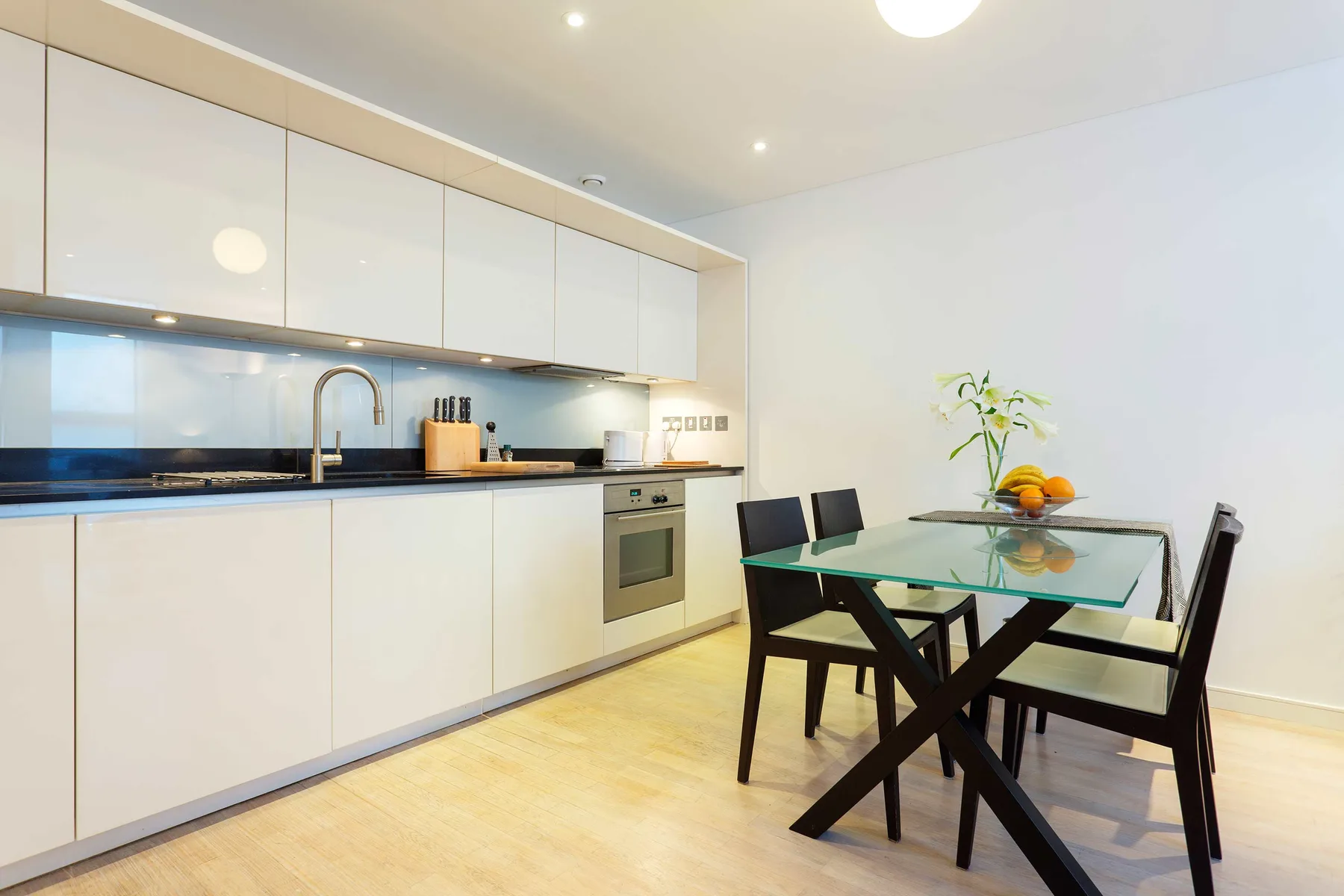 A bright kitchen with a dining table and chairs beside the counter.