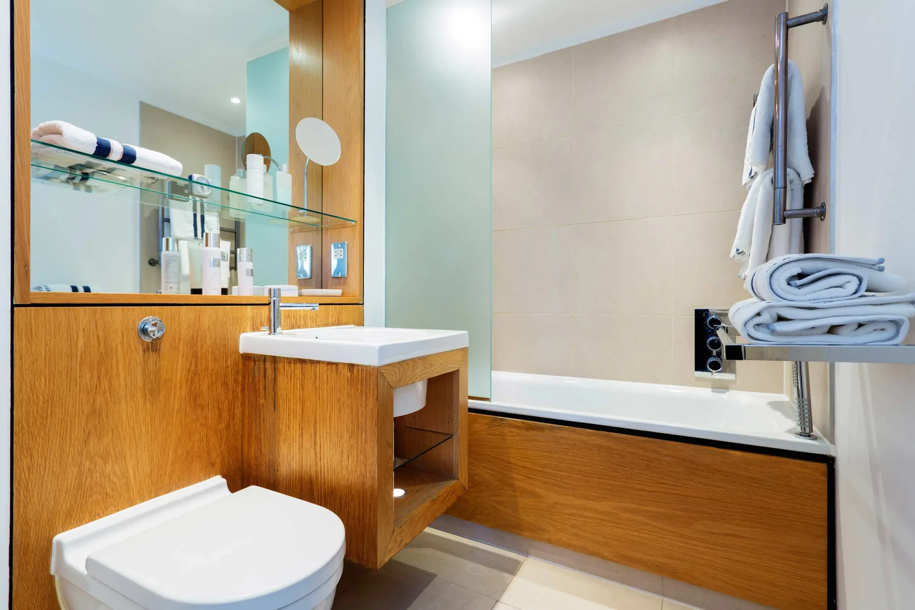 A bathroom with a bathtub, sink, and wood cabinetry.