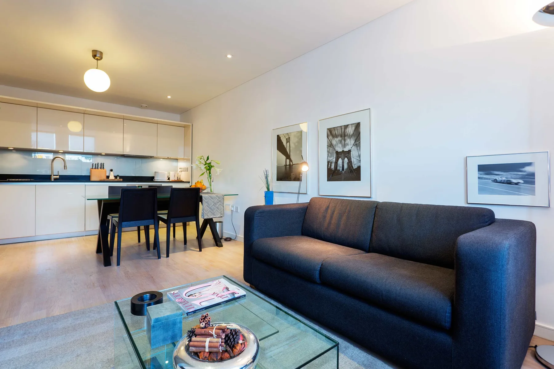 A bright living and dining area with dark seating and an open kitchen.