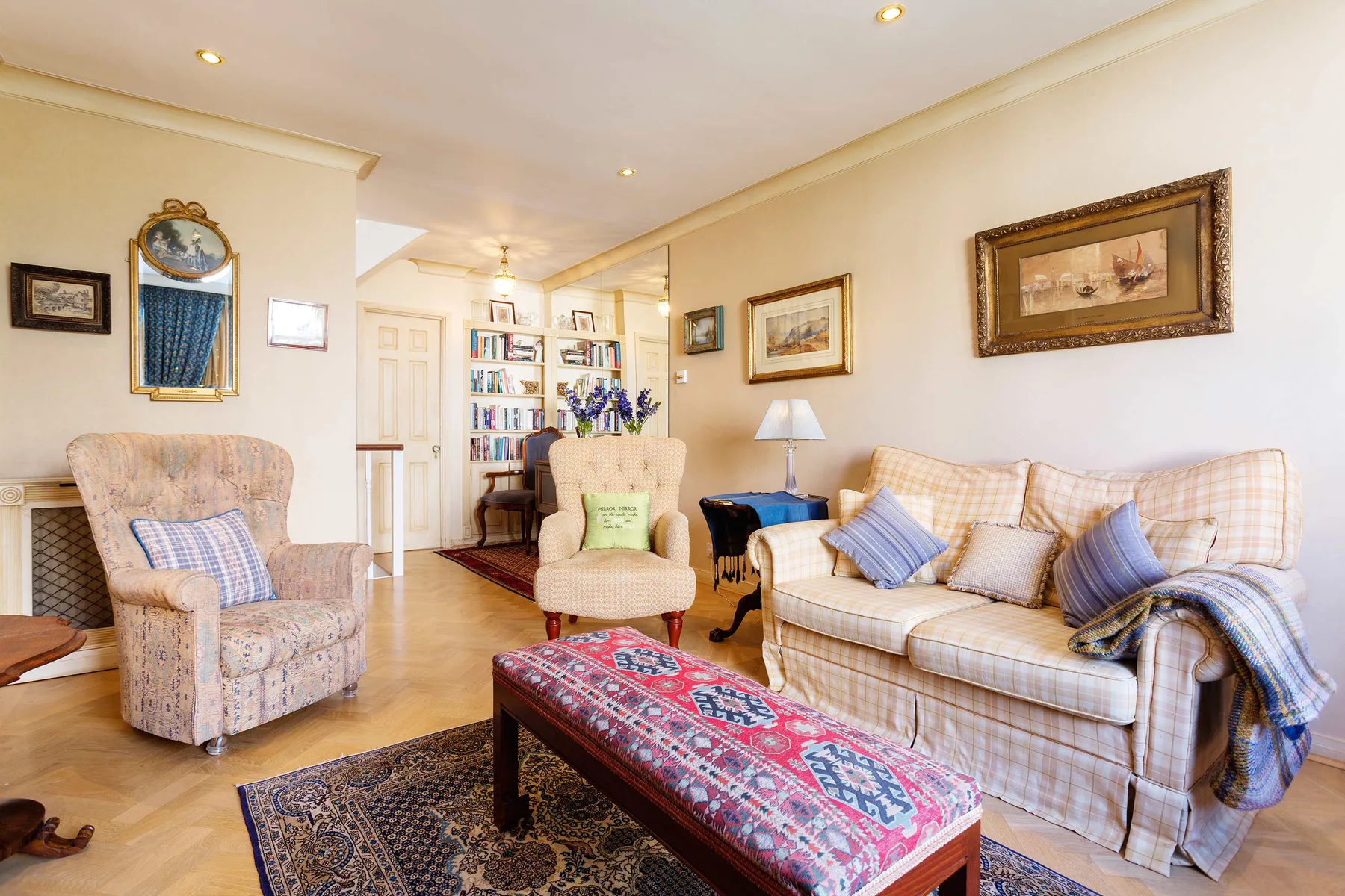 A warmly decorated living room with upholstered seating and a patterned coffee table.
