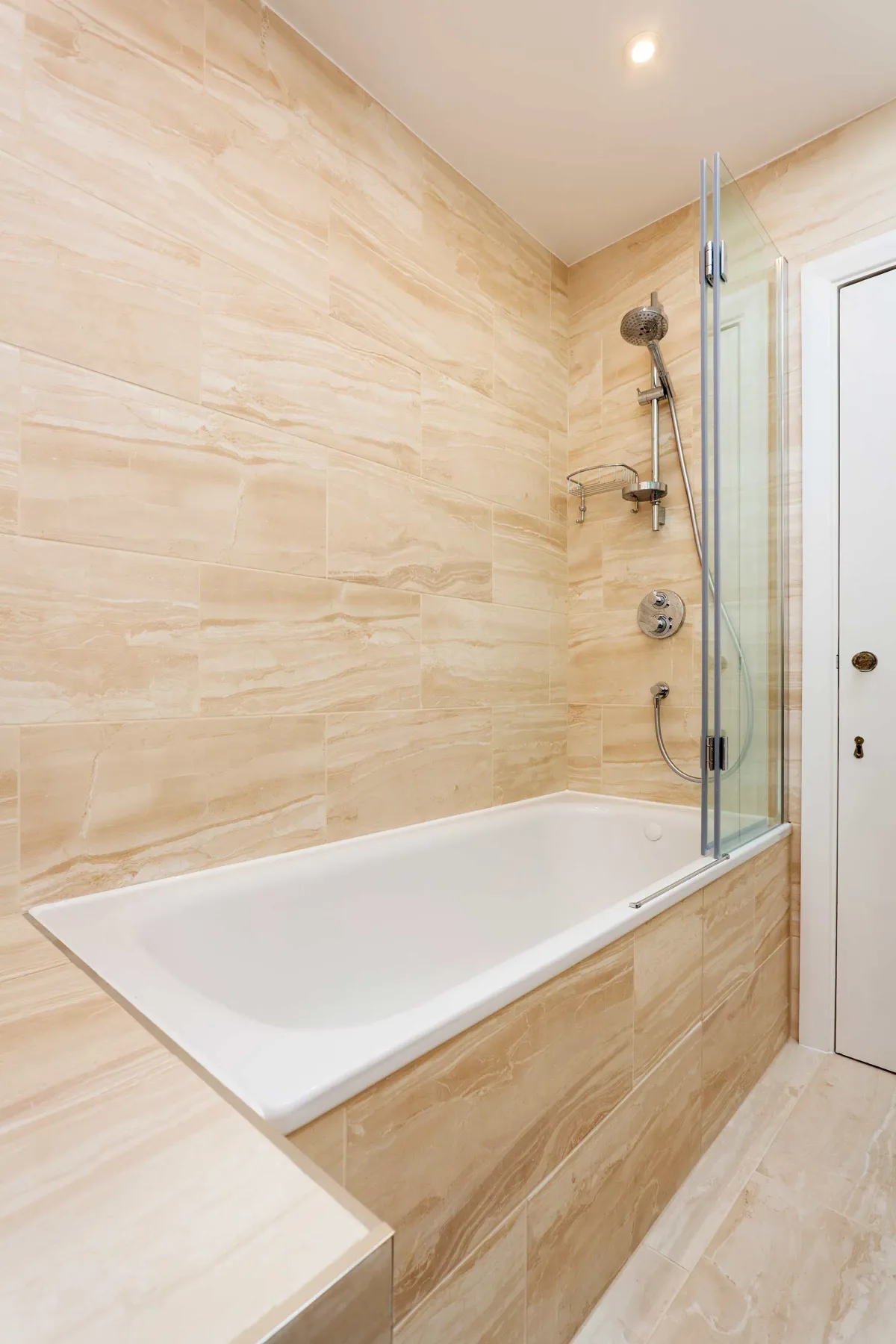 A tiled bathroom with a bathtub and wall-mounted shower.