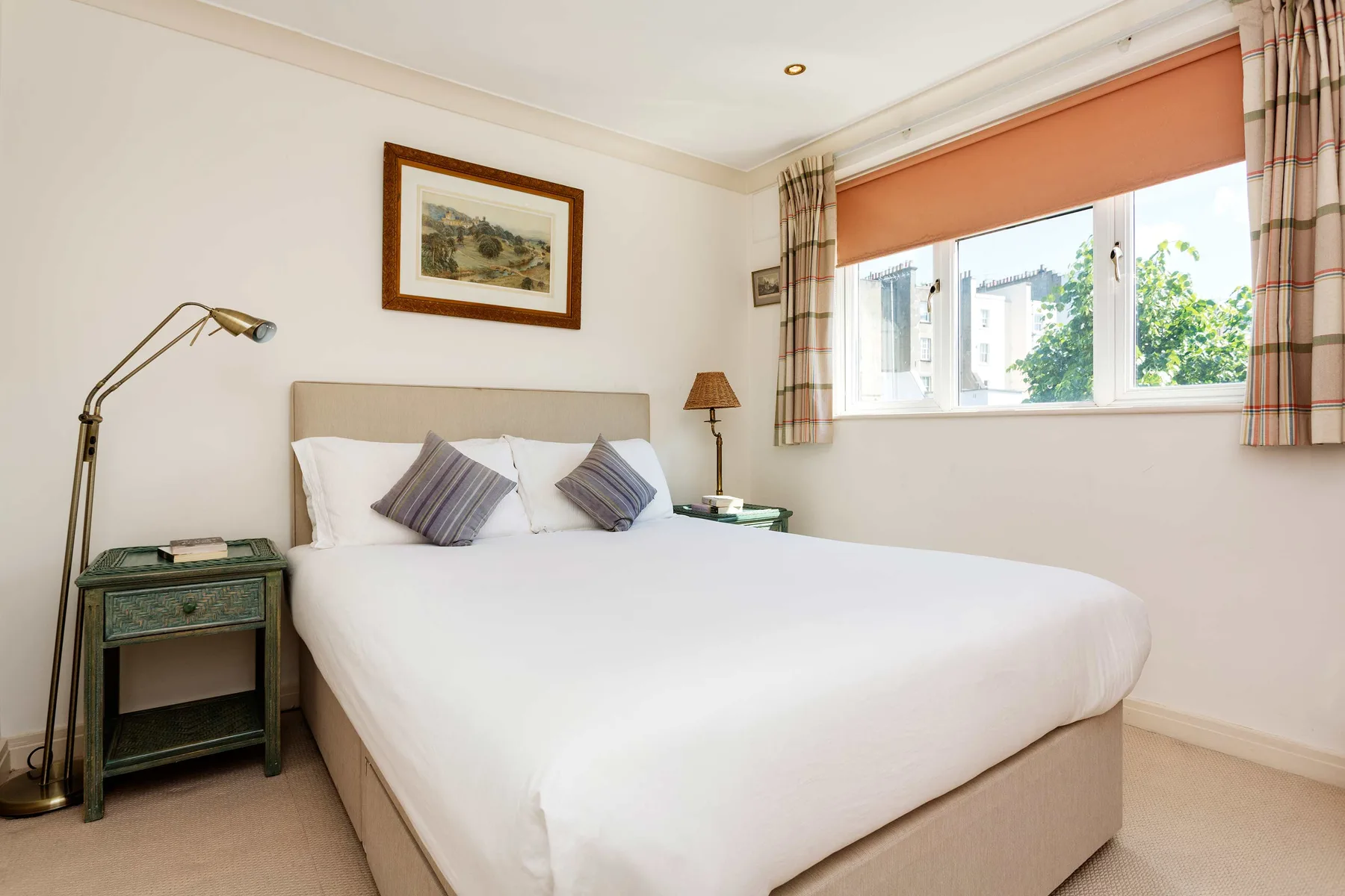A bedroom with a neatly made bed beside a large window.